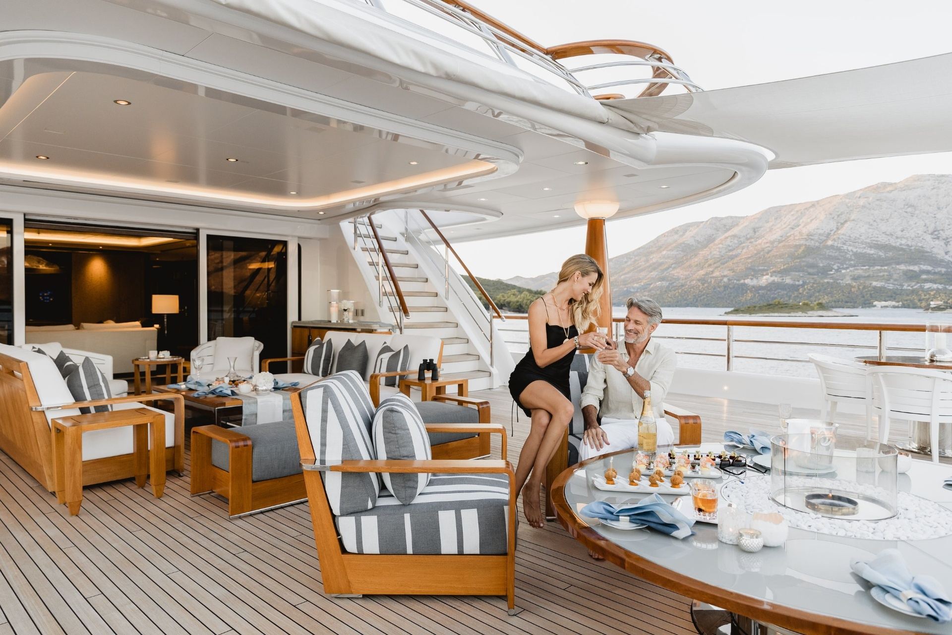 French Riviera Yacht Charter for Couples: Romantic Escapes at Sea Couple enjoying sunset drinks on yacht deck with French Riviera coastline