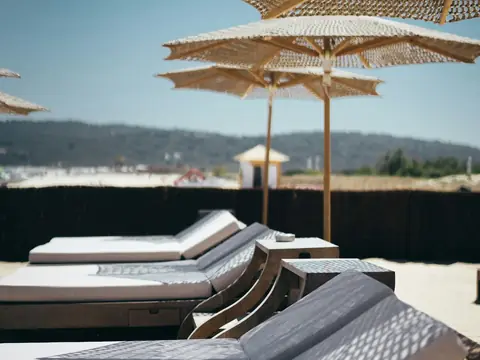 Mood photo (not the venue): White cushioned loungers under parasols