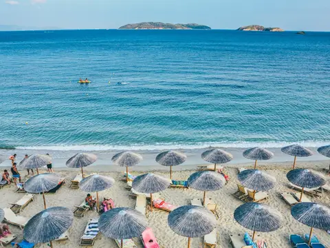 Mood photo (not the venue): Straw parasols and loungers facing a calm sea