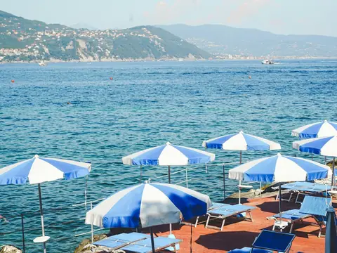 Mood photo (not the venue): Parasols and loungers on a rocky seafront terrace