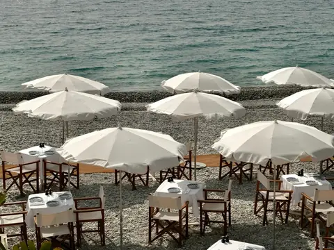 Mood photo (not the venue): Beach restaurant tables under white parasols