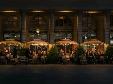 Mood photo (not the venue): Diners under striped parasols on a terrace at night