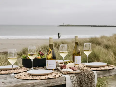 Mood photo (not the venue): White wine and plates on a table by the sea